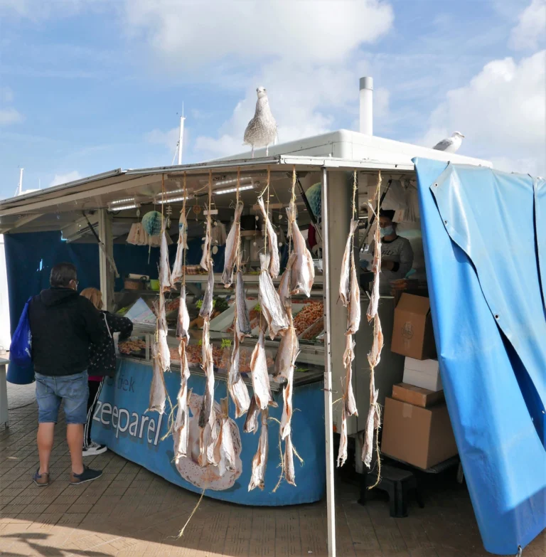 Blue fish stall with dried fish hanging at the front and a gull on the roof