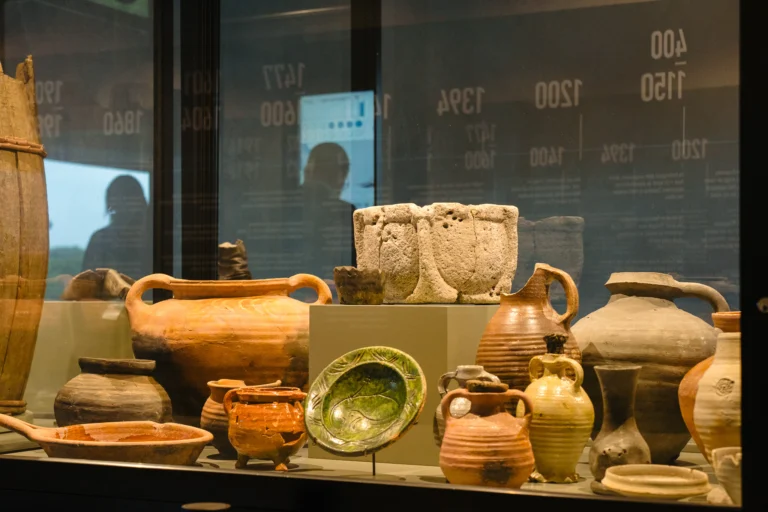 Display case of excavated medieval jugs, bowls and a green glazed dish from the lost fishing village