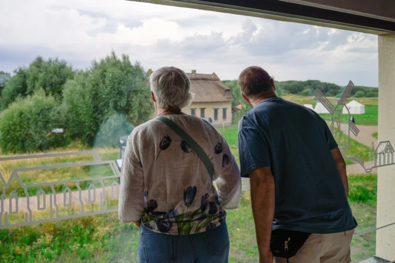 Two visitors looking out from the museum window over the reconstructed thatched fishermen's houses