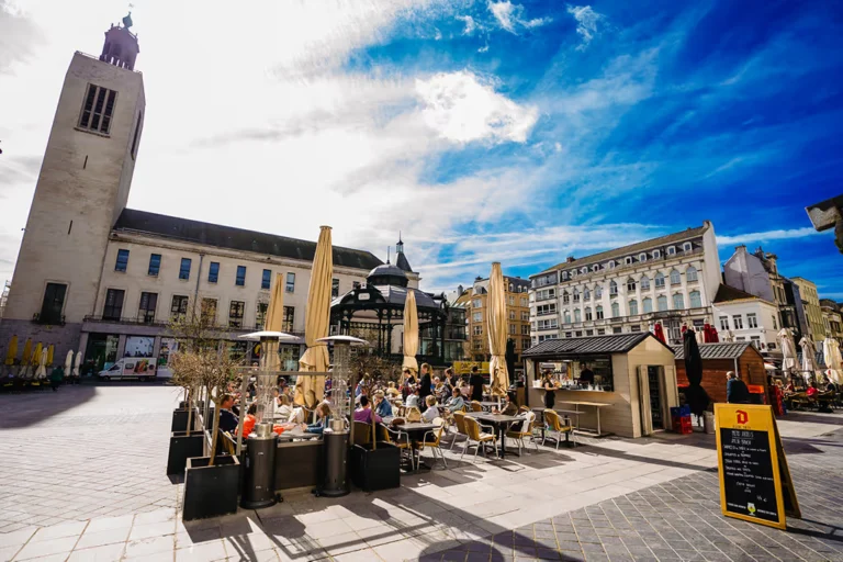 Sunny café terraces on Ostend's Wapenplein, with the bandstand and a historic church tower behind