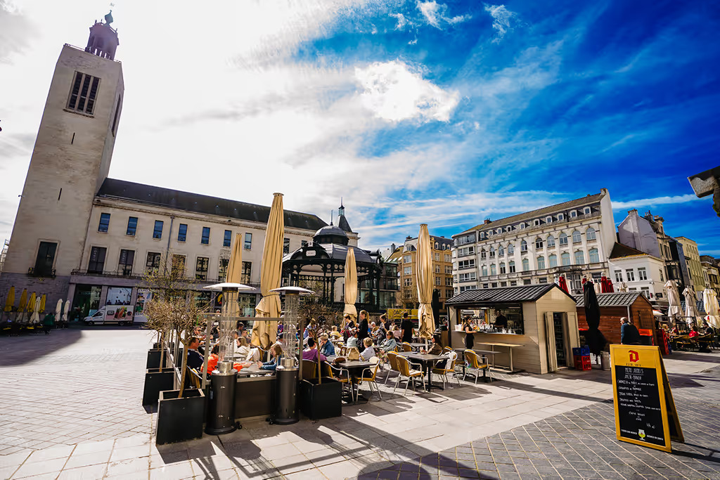 Sunny café terraces on Ostend's Wapenplein, with the bandstand and a historic church tower behind
