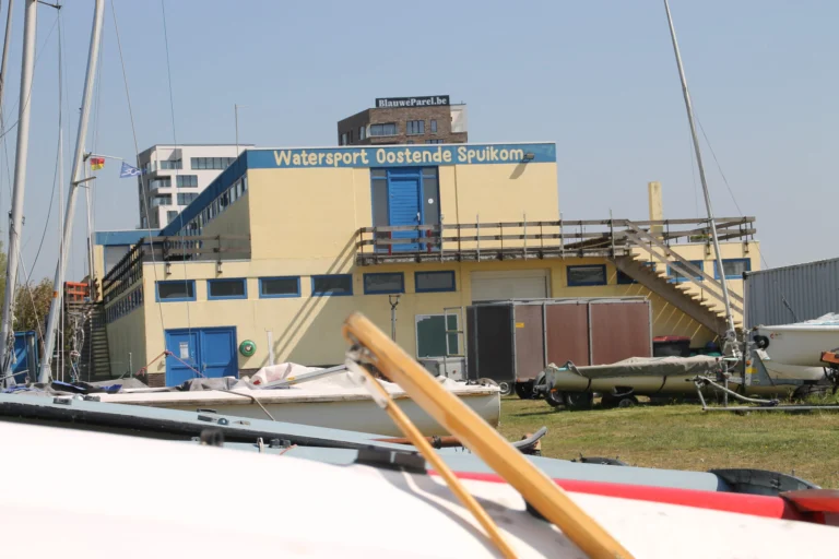 Yellow and blue Watersport Oostende Spuikom clubhouse with dinghies on the grass in front