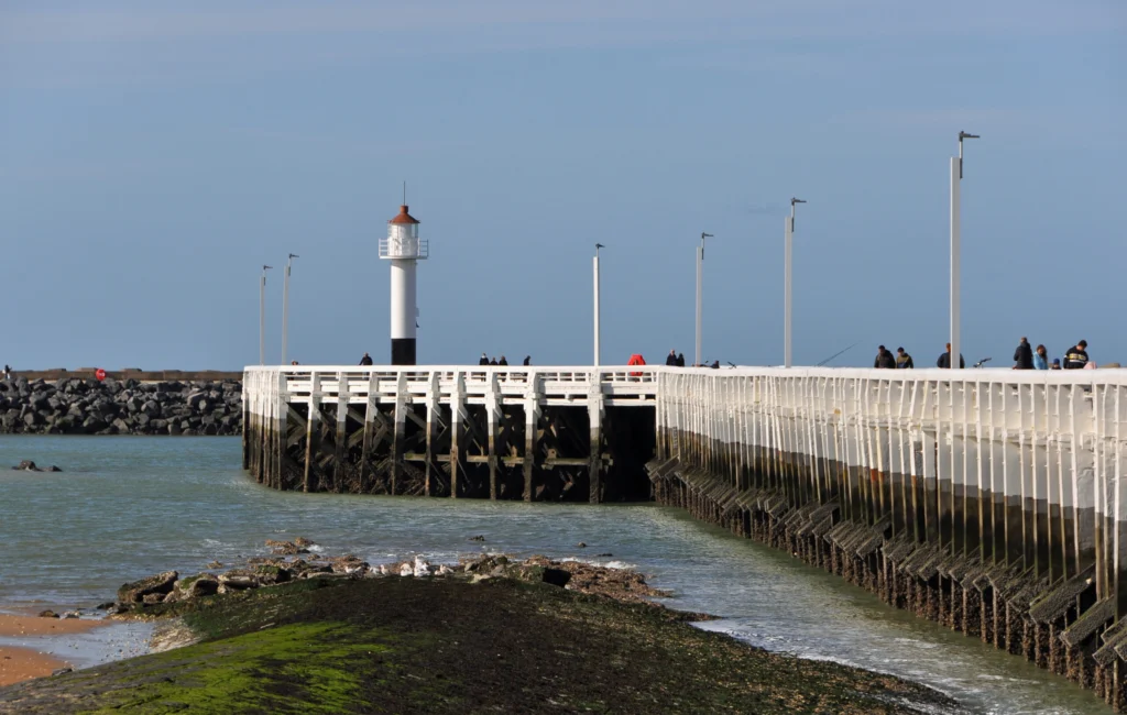 The white wooden West Pier on its timber piles, with the small red-topped lighthouse at its end
