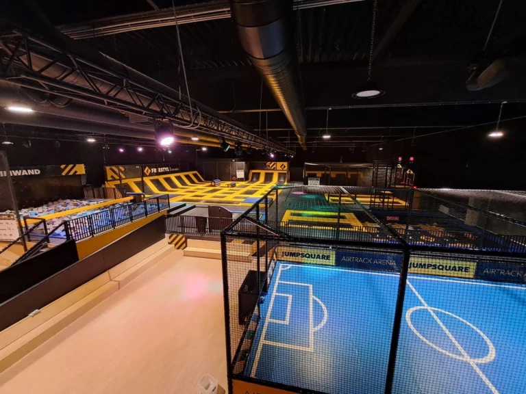 Elevated view over the hall with the netted Jumpsquare arena and trampolines beyond