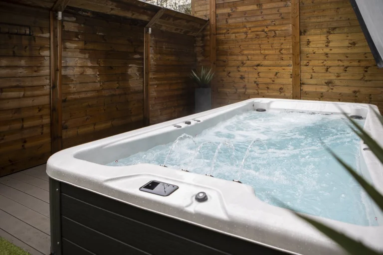 Bubbling outdoor swim spa on a deck in a garden enclosed by a high timber fence